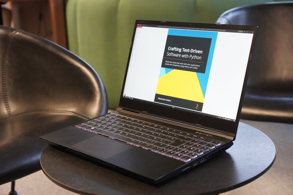 A close-up of a laptop on a table, displaying a book on test-driven software with Python, set in a comfortable environment.